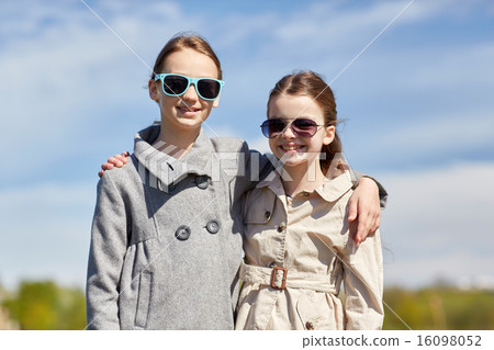 happy little girls in sunglasses hugging outdoors 16098052
