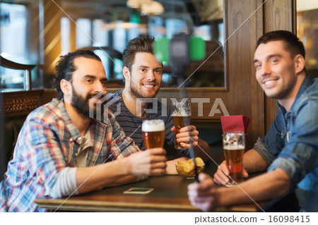 friends taking selfie and drinking beer at bar 16098415