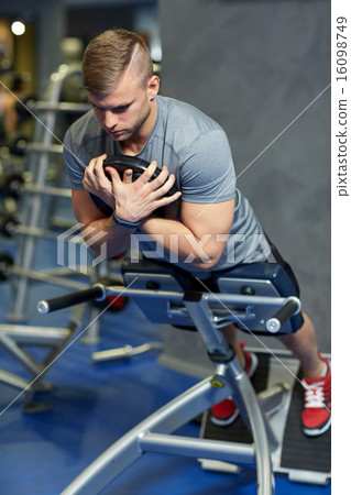 young man flexing back muscles on bench in gym 16098749