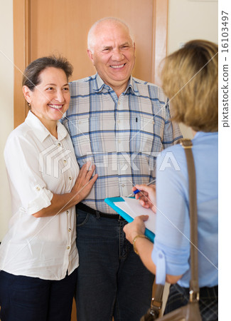 couple answering questions of employee in door 16103497