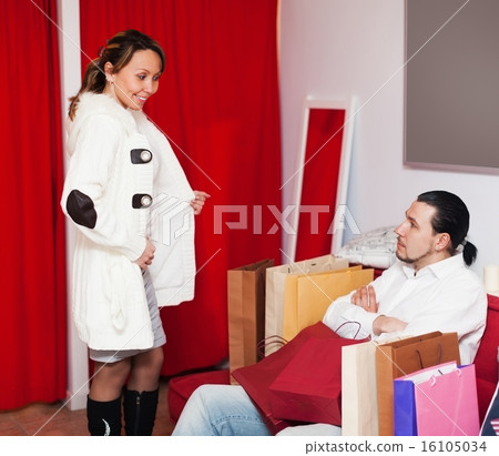 Man and woman choosing coat in fitting-room Man and woman choosing coat in fitting-room 16105034