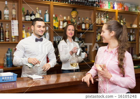 Girl standing at bar with glass of wine. 16105248