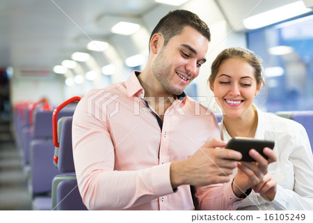 Young couple with smartphones in train 16105249