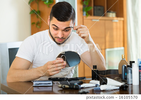 Handsome man remove hair with pincers. Handsome man remove hair with pincers. 16105570