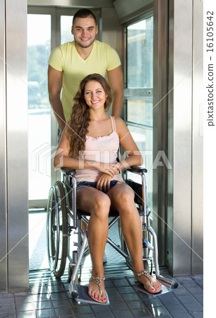 Couple with wheelchair in elevator 16105642