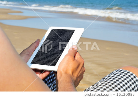 reading on an e-book on the beach 16120083