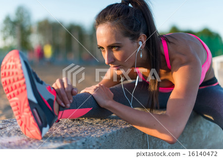 Athletic woman stretching her hamstring, legs exercise training fitness before workout outside on a 16140472