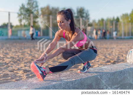 Athletic woman stretching her hamstring, legs exercise training fitness before workout outside on a 16140474