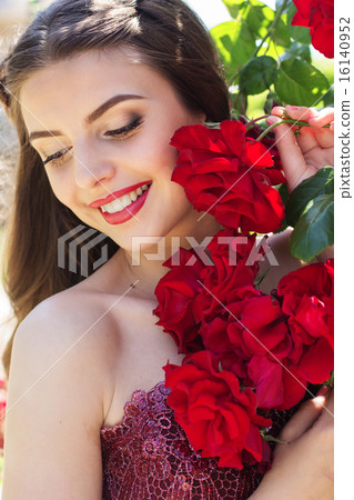 Beautiful young woman is posing near roses in a garden Beautiful young woman is posing near roses in a garden 16140952