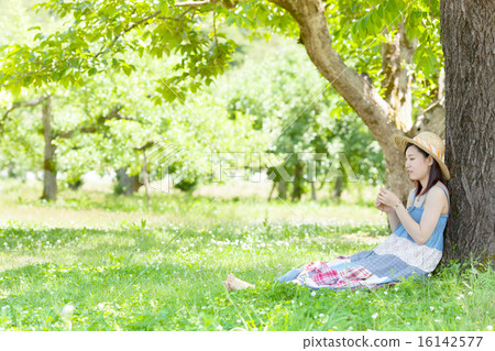 A woman sitting and resting in the shade of the early summer park A woman sitting and resting in the shade of the early summer park 16142577