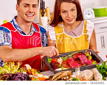 Couple cooking raw meat dinner at kitchen. 16163081