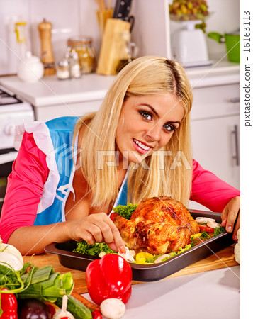 Woman cooking chicken at kitchen. Woman cooking chicken at kitchen. 16163113