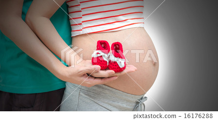 Loving couple hands with baby shoe on pregnant belly Loving couple hands with baby shoe on pregnant belly 16176288