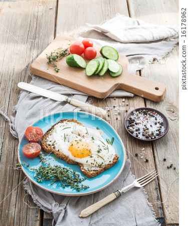 Breakfast set. Whole grain andwich with fried egg, vegetables and herbs on rustic wooden table 16178962