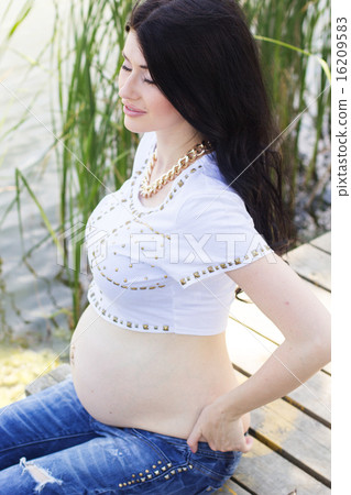 Pregnant pretty woman sitting on bridge near river Pregnant pretty woman sitting on bridge near river 16209583