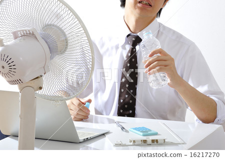 A businessman who works while hanging a fan in a hot summer office A businessman who works while hanging a fan in a hot summer office 16217270