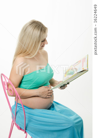 pregnant young woman reading a book sitting on chair pregnant young woman reading a book sitting on chair 16224649