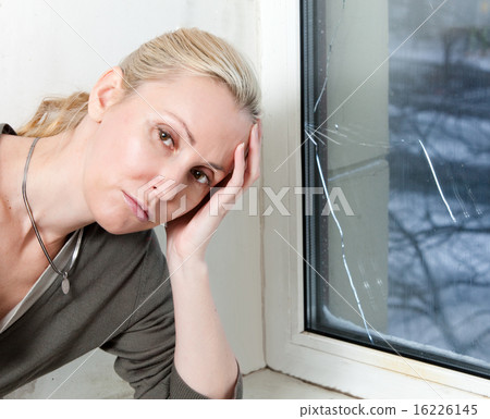 sad young woman near a window with the burst, brok 16226145