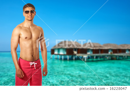 Man on beach with water bungalows Man on beach with water bungalows 16228047