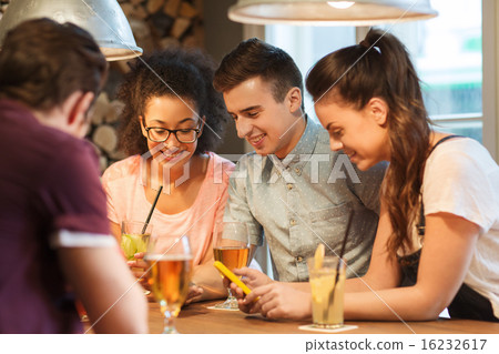 happy friends with smartphones and drinks at bar 16232617