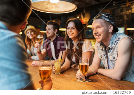 happy friends with drinks talking at bar or pub 16232769
