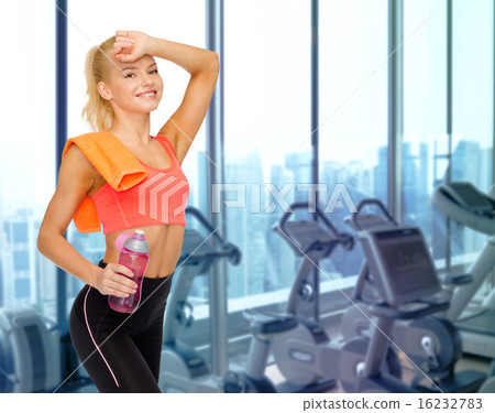 happy woman with bottle of water and towel in gym happy woman with bottle of water and towel in gym 16232783