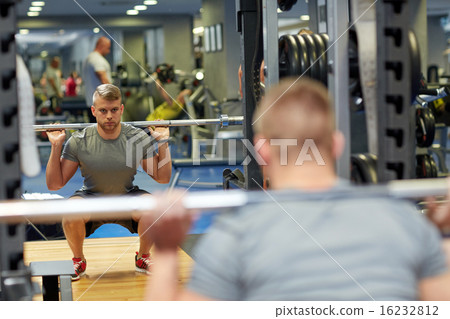 young man flexing muscles with barbell in gym young man flexing muscles with barbell in gym 16232812