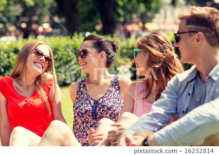 group of smiling friends outdoors sitting in park group of smiling friends outdoors sitting in park 16232814