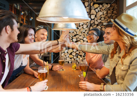happy friends with drinks making high five at bar 16233356