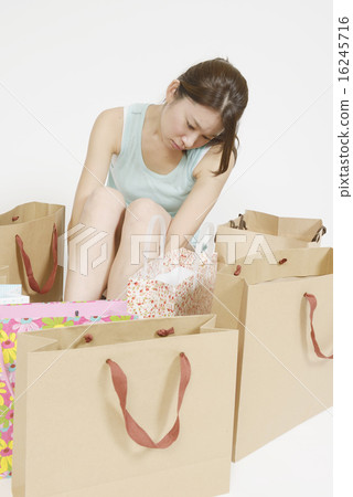 A young lady disappointed in front of a lot of shopping bags A young lady disappointed in front of a lot of shopping bags 16245716