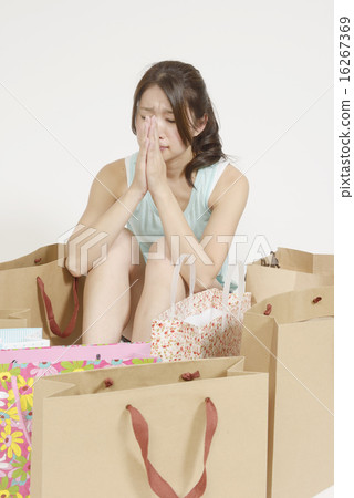 A young woman apologizing in front of a lot of shopping bags A young woman apologizing in front of a lot of shopping bags 16267369