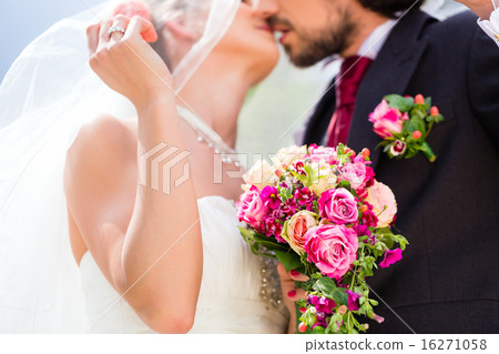 Bridal pair kissing under veil at wedding 16271058