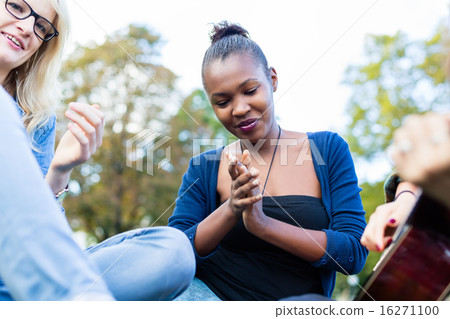 Friends clapping along to music in park Friends clapping along to music in park 16271100