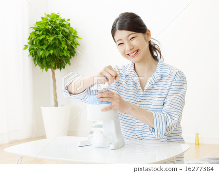 A woman who makes a shaved ice in a room A woman who makes a shaved ice in a room 16277384