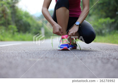 young asian woman tying shoelace young asian woman tying shoelace 16278992