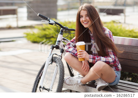 Young woman drinking coffee on a bicycle trip 16286517