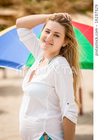 cute woman posing on beach against sun umbrellas 16287829