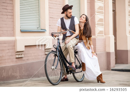 Young couple sitting on a bicycle against the wall Young couple sitting on a bicycle against the wall 16293505