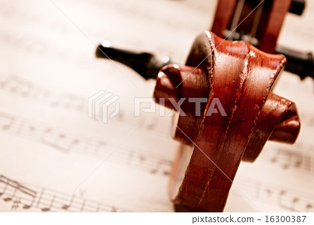 Carved Wooden Violin Scroll Resting on Sheet Music 16300387