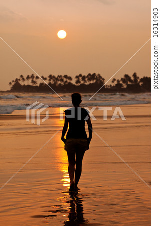Woman walking on beach at sunset 16314903