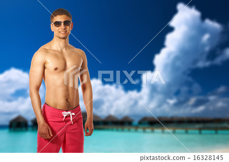 Man on beach with water bungalows 16328145