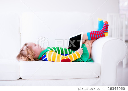 Little girl with tablet computer on a white couch 16343960