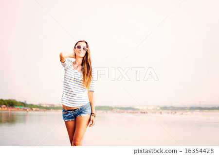 Beautifil young woman walking along the beach at sunset enjoing summer vacation 16354428