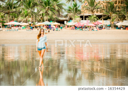 Beautifil young woman walking along the beach at sunset enjoing summer vacation 16354429