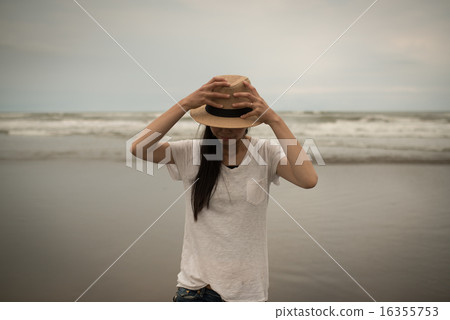 拿著一個帽子的婦女在海 拿著一個帽子的婦女在海 16355753