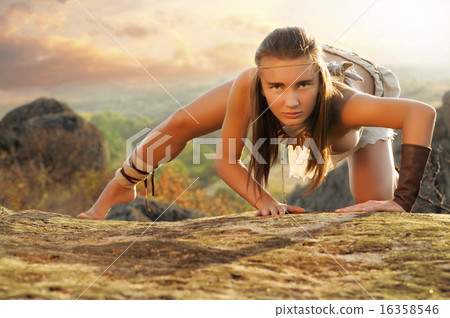 Primitive woman on a rock at the sunset. Amazon woman Primitive woman on a rock at the sunset. Amazon woman 16358546