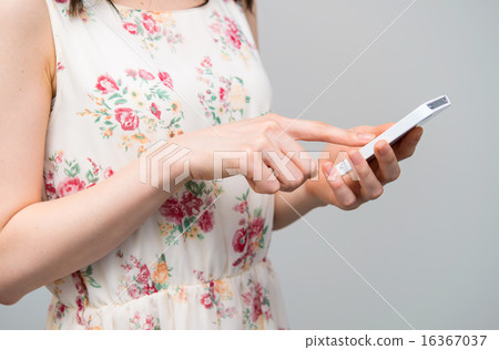 A woman in a floral dress operating a smartphone A woman in a floral dress operating a smartphone 16367037