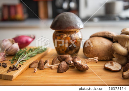Closeup on jar of pickled mushroom on cutting board Closeup on jar of pickled mushroom on cutting board 16378134