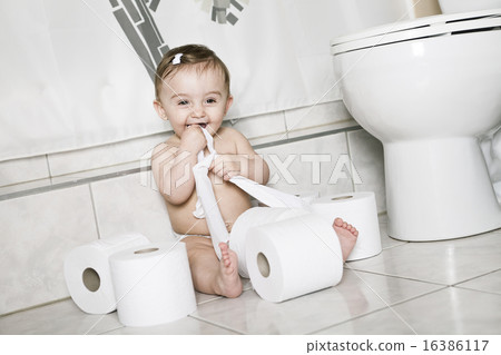 Toddler ripping up toilet paper in bathroom 16386117