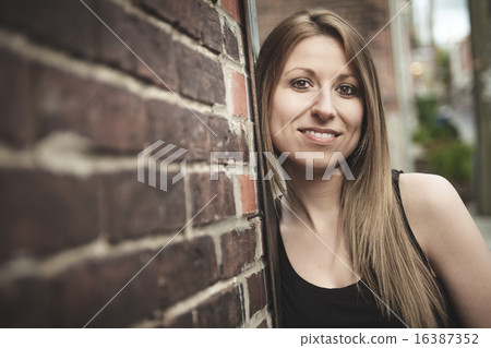 Beautiful modern girl near the brickwall.  16387352